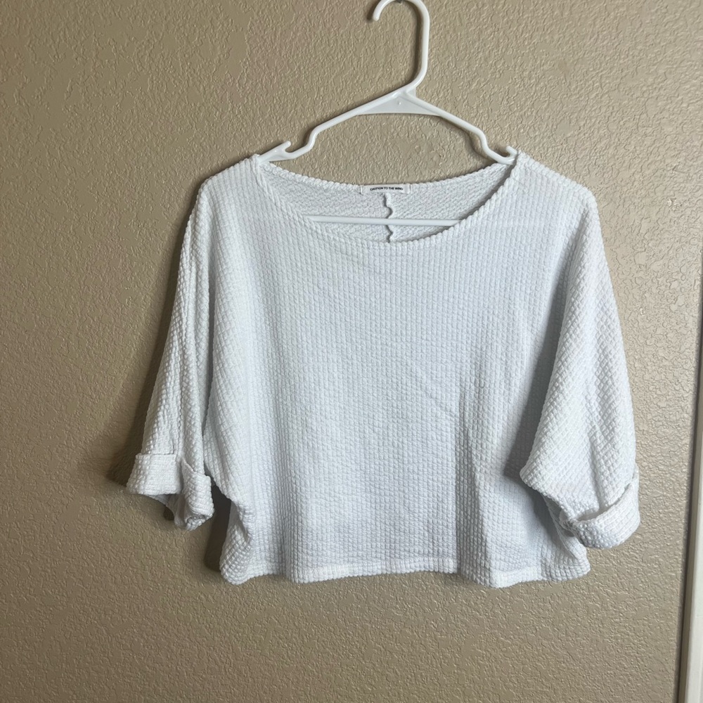 White crop top, short sleeves but hits at the elbow.
